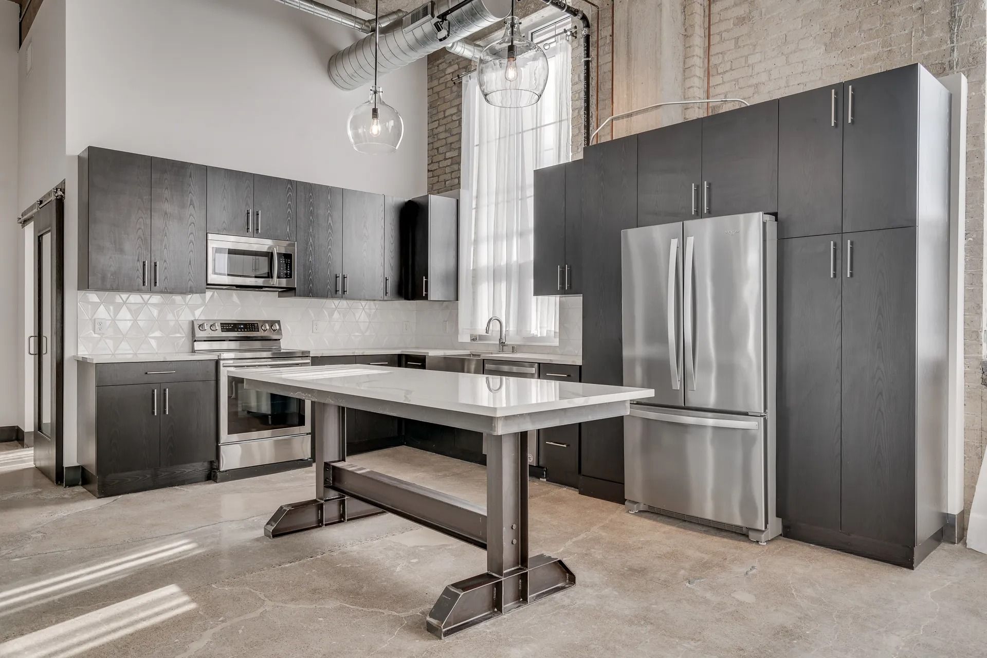 Beautiful kitchen area with stainless steel appliances and island lighting inside MAX Minneapolis apartments